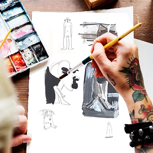 Tätowierte Hand, die mit einem Pinsel Studien macht